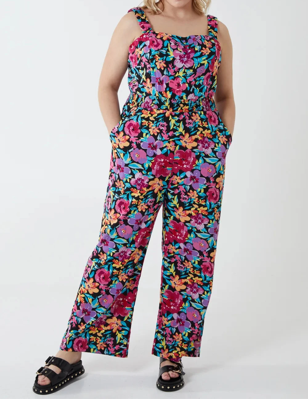 Woman wearing a colorful floral jumpsuit on a white background