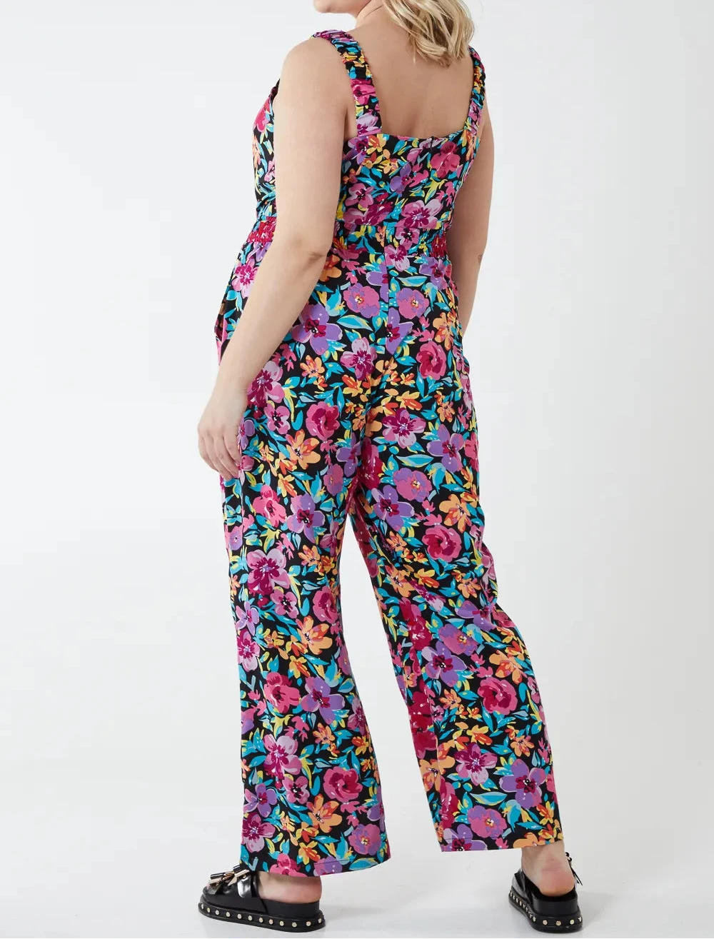 Woman wearing a colorful floral jumpsuit on a white background