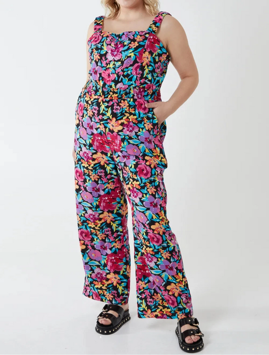 Woman wearing a colorful floral jumpsuit on a white background